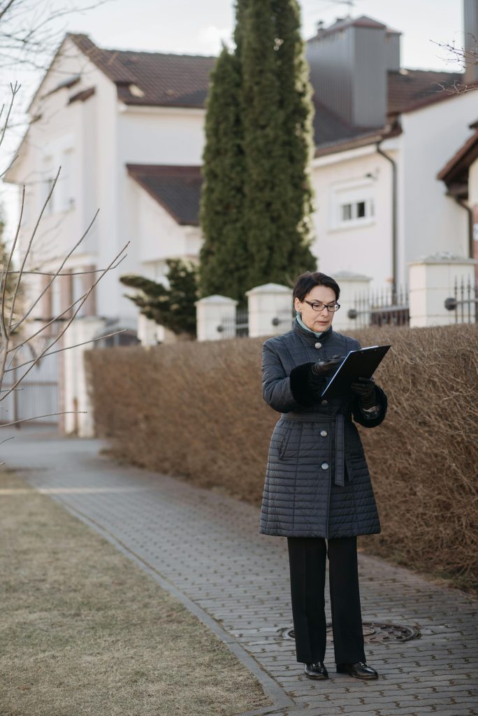 Realtor woman reviewing documents on sidewalk in winter urban setting.